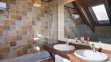 A bathroom with two sinks, a shower, and a skylight.