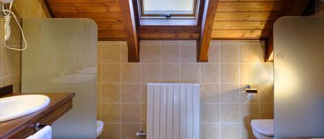 Un baño con tragaluz, techo de madera y radiador blanco.