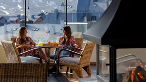 Two people sitting at a table with a view of a snowy mountain landscape through large windows. - Snö Aragon Hills (Sallent de Gallego)