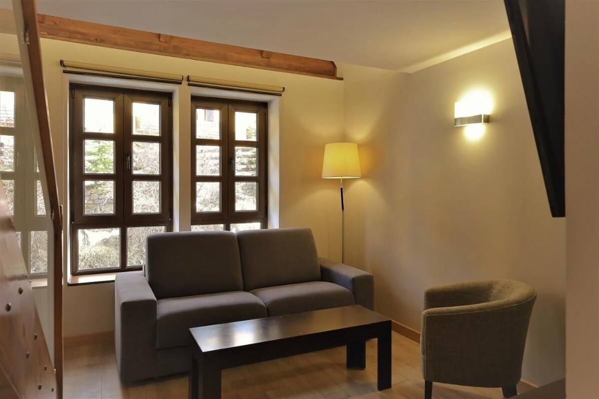 Una habitación con sofá, una mesita, una lámpara y una silla.