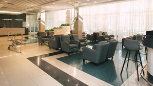 Eine moderne Lobby mit Empfangstresen, Sitzgelegenheiten und großen Fenstern.