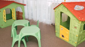 Ein Zimmer mit zwei Spielhäusern, einem Tisch und Stühlen.