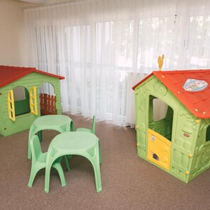 A room with two playhouses, a table, and chairs. - Nufarul (Baile Felix)