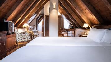 Un dormitorio con una cama grande, vigas de techo de madera, un escritorio y una silla.