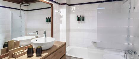 A modern bathroom with a wooden vanity, two sinks, a bathtub, and a shower.