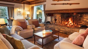 Una sala de estar acogedora con chimenea de piedra, asientos cómodos y vistas al exterior.