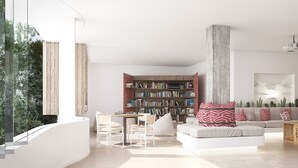 A modern living room with a white sofa, a wooden coffee table, and a bookshelf. - Apartamentos Castaví (Formentera)