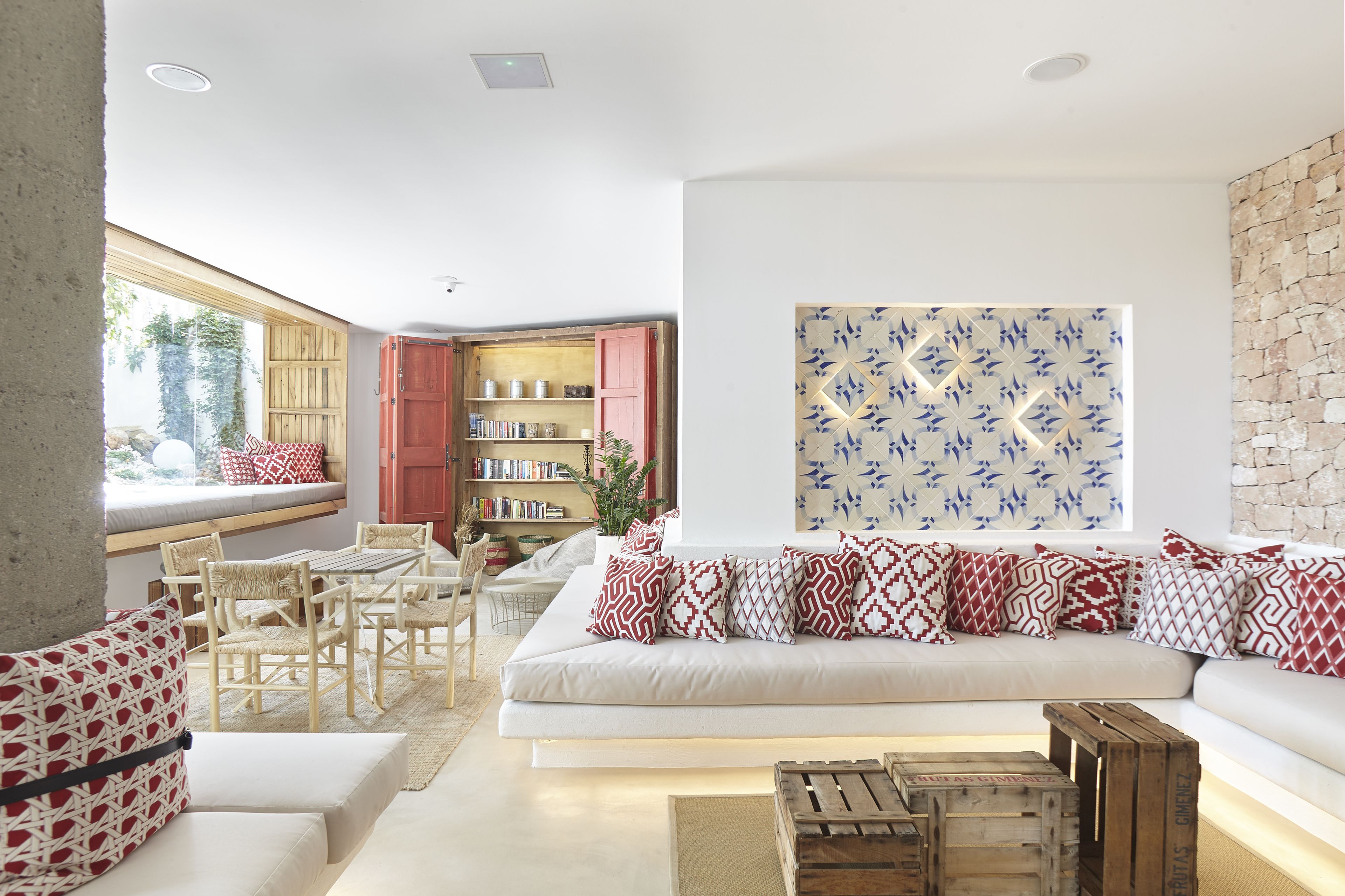 A modern living room with a white sofa, patterned cushions, wooden furniture, and a bookshelf.