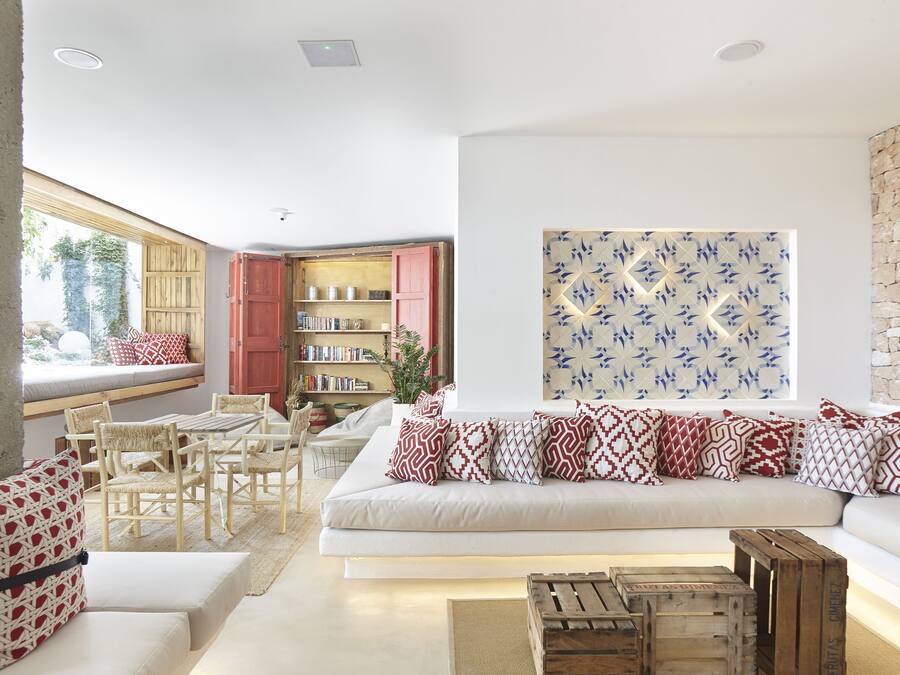 Una sala de estar moderna con un sofá blanco, cojines estampados, muebles de madera y una estantería.