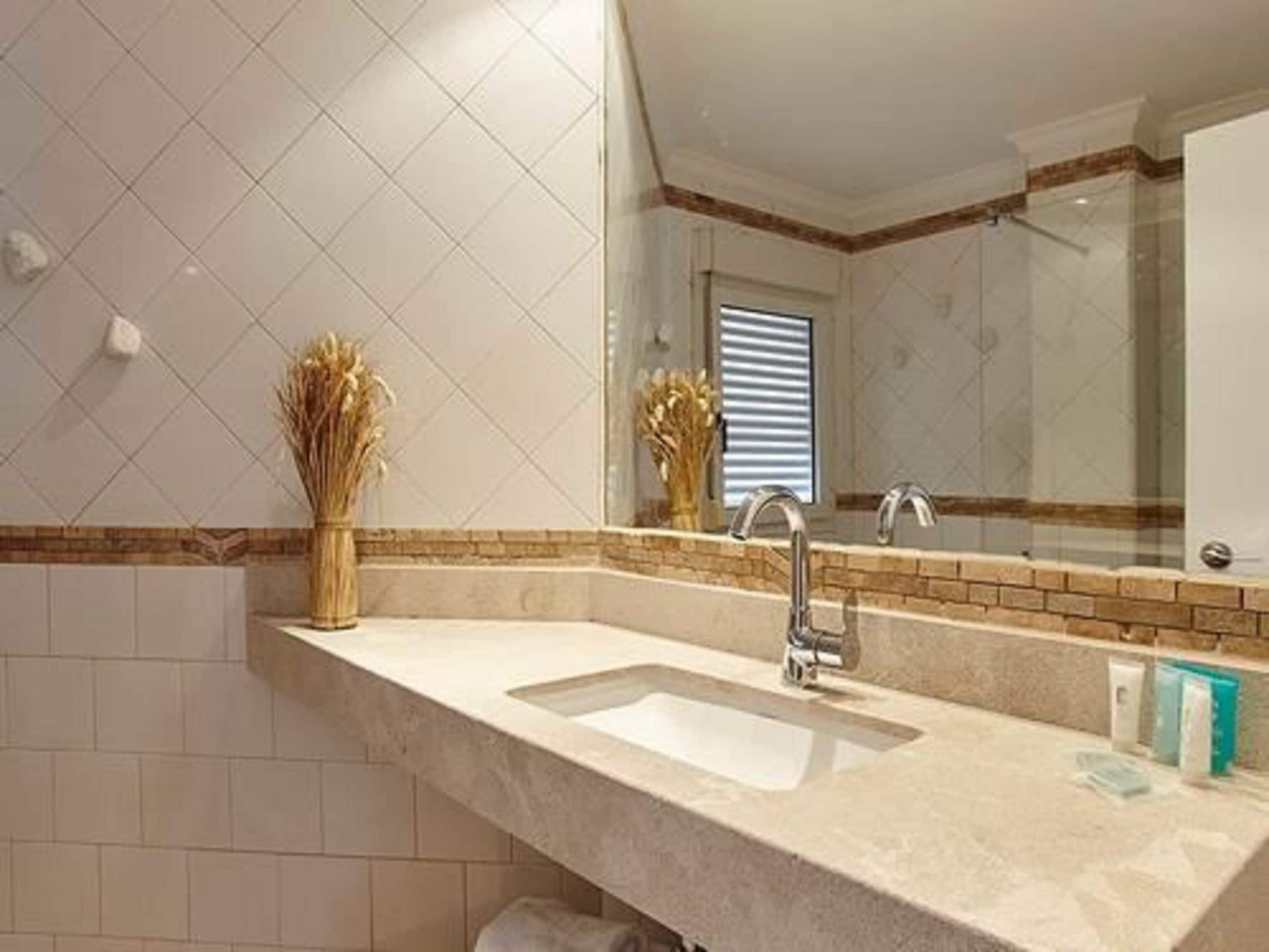 A bathroom with a large mirror, a sink, and a towel rack.