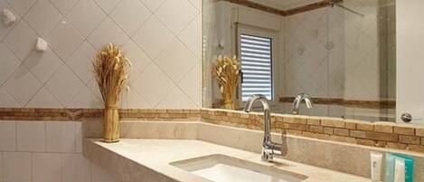 A bathroom with a large mirror, a sink, and a towel rack.