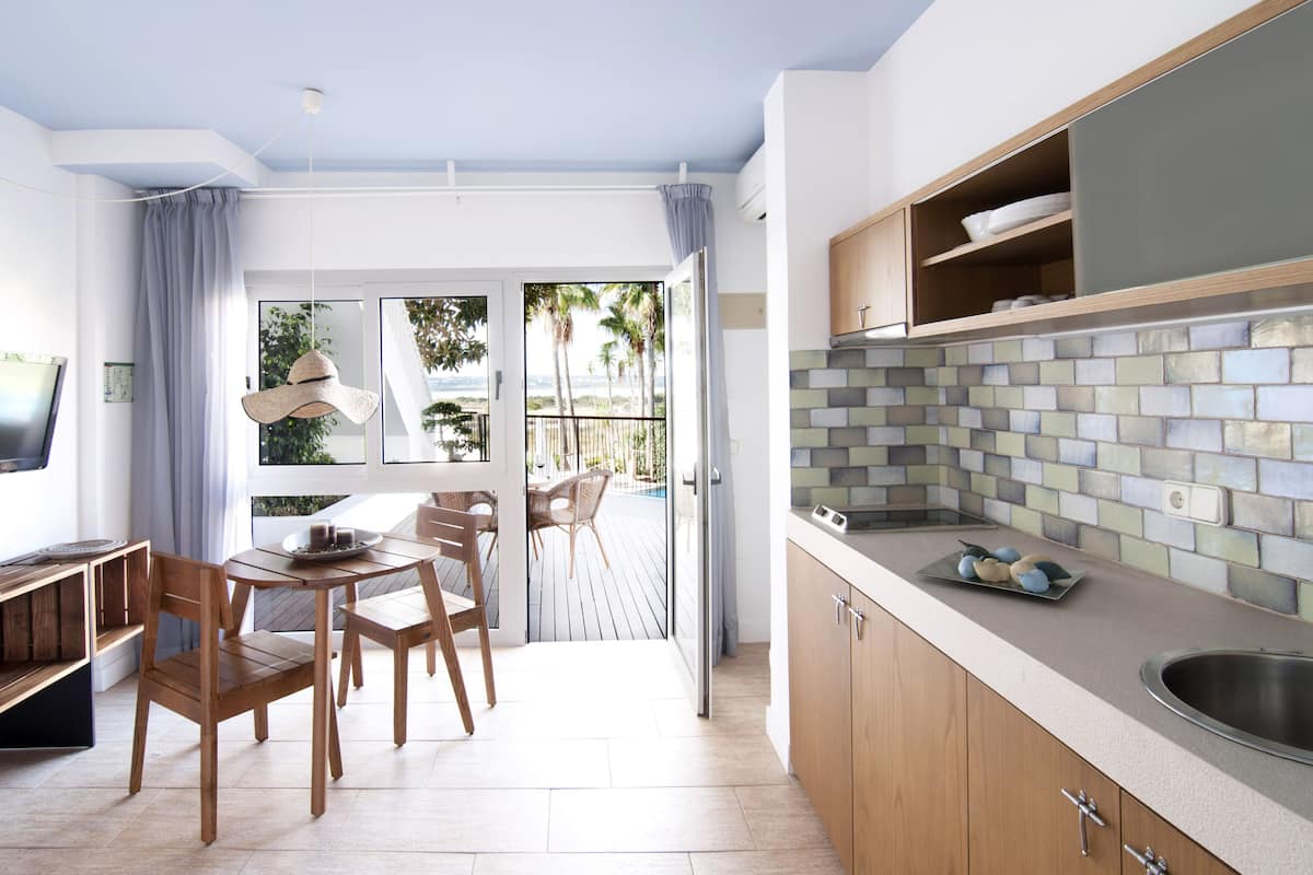 Una cocina moderna con armarios de madera, salpicadero de azulejos y una zona de comedor con mesa y sillas.