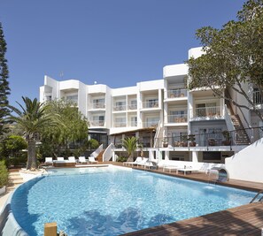 Un hotel con piscina, varios balcones y una escalera que conduce a los pisos superiores.