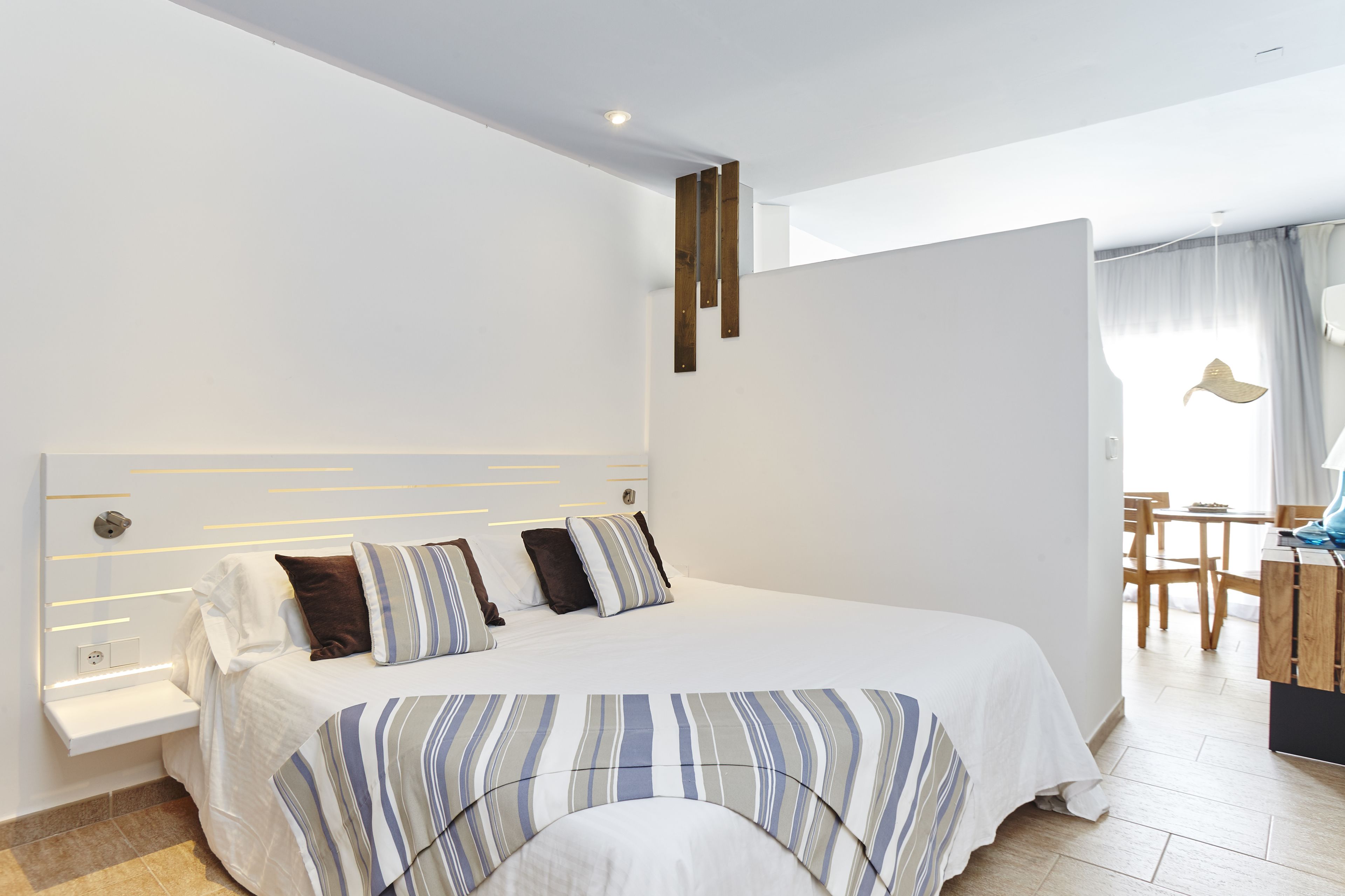 A modern hotel room with a large bed, a bedside table, and a desk area.