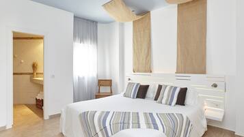 Un dormitorio moderno con una cama grande, un cabecero de madera y un baño visible a través de una puerta abierta.