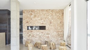 A modern interior with a stone wall, wooden stumps, and a minimalist design. - Apartamentos Castaví (Formentera)