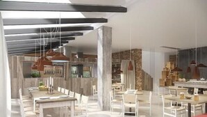 A modern dining area with white furniture, pendant lighting, and a stone accent wall. - Apartamentos Castaví (Formentera)