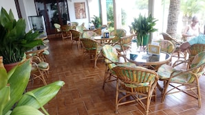 A spacious indoor area with wicker furniture and potted plants. - Oasis D'or (Santanyi)