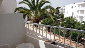 A balcony with white railings, a small round table, and two white chairs. - Oasis D'or (Santanyi)