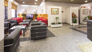 Um saguão de hotel com áreas de estar, televisão e obras de arte nas paredes.