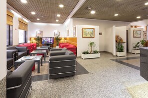 A hotel lobby with seating areas, a television, and artwork on the walls. - Anjos (Lisbon)