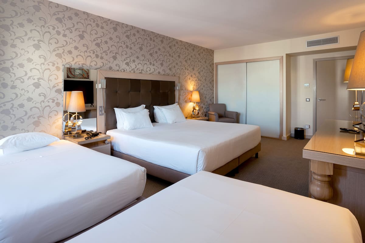 A hotel room with two beds, a desk, a chair, and a wardrobe.