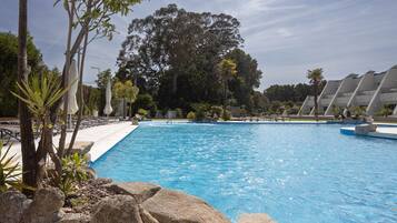 Una piscina con agua cristalina azul, rodeada de rocas y plantas.