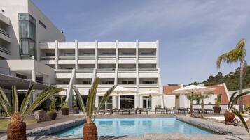 Een buitenzwembad, parasols bij het zwembad en ligstoelen