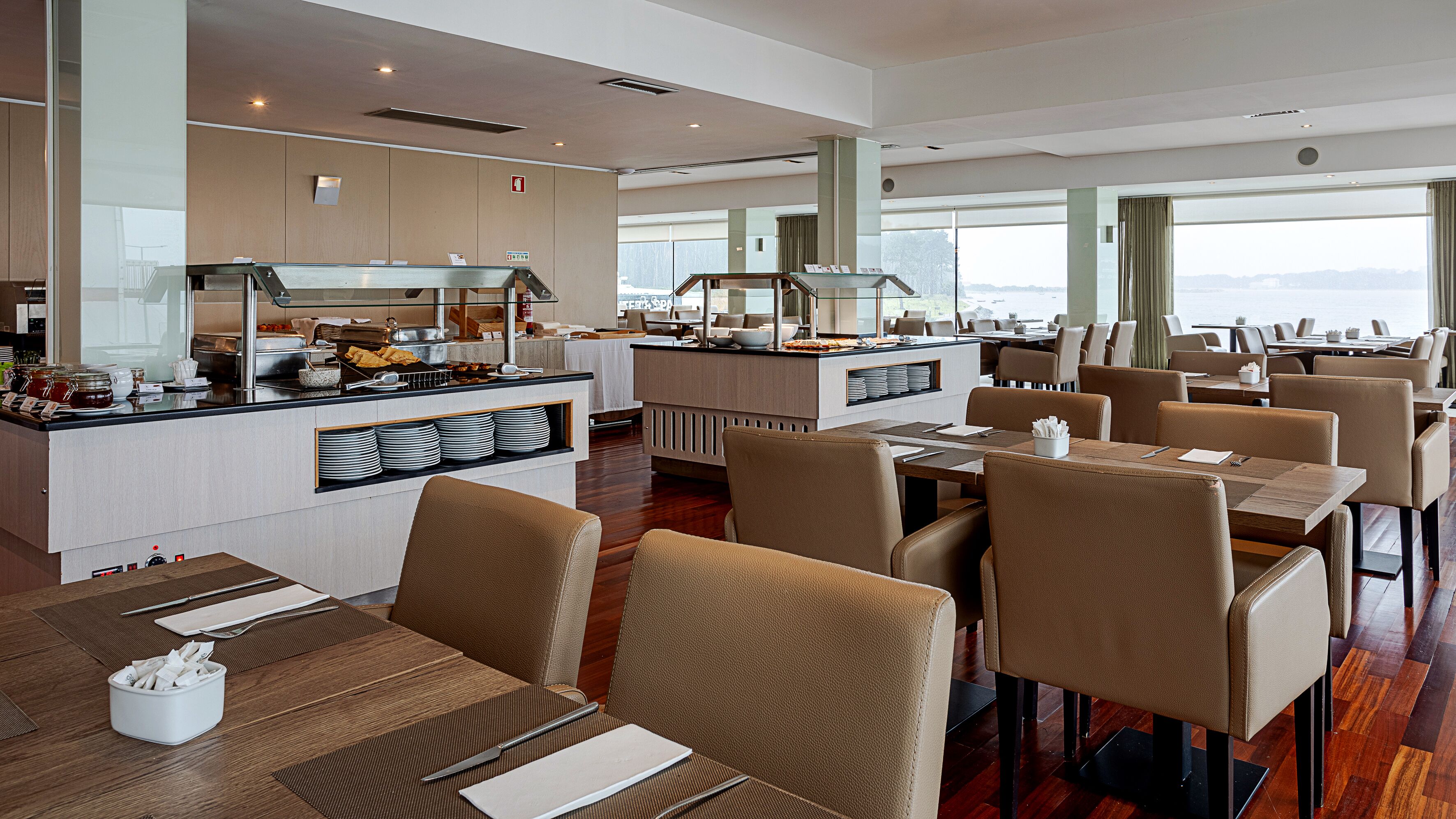 A modern restaurant with a central counter, dining tables, and chairs.