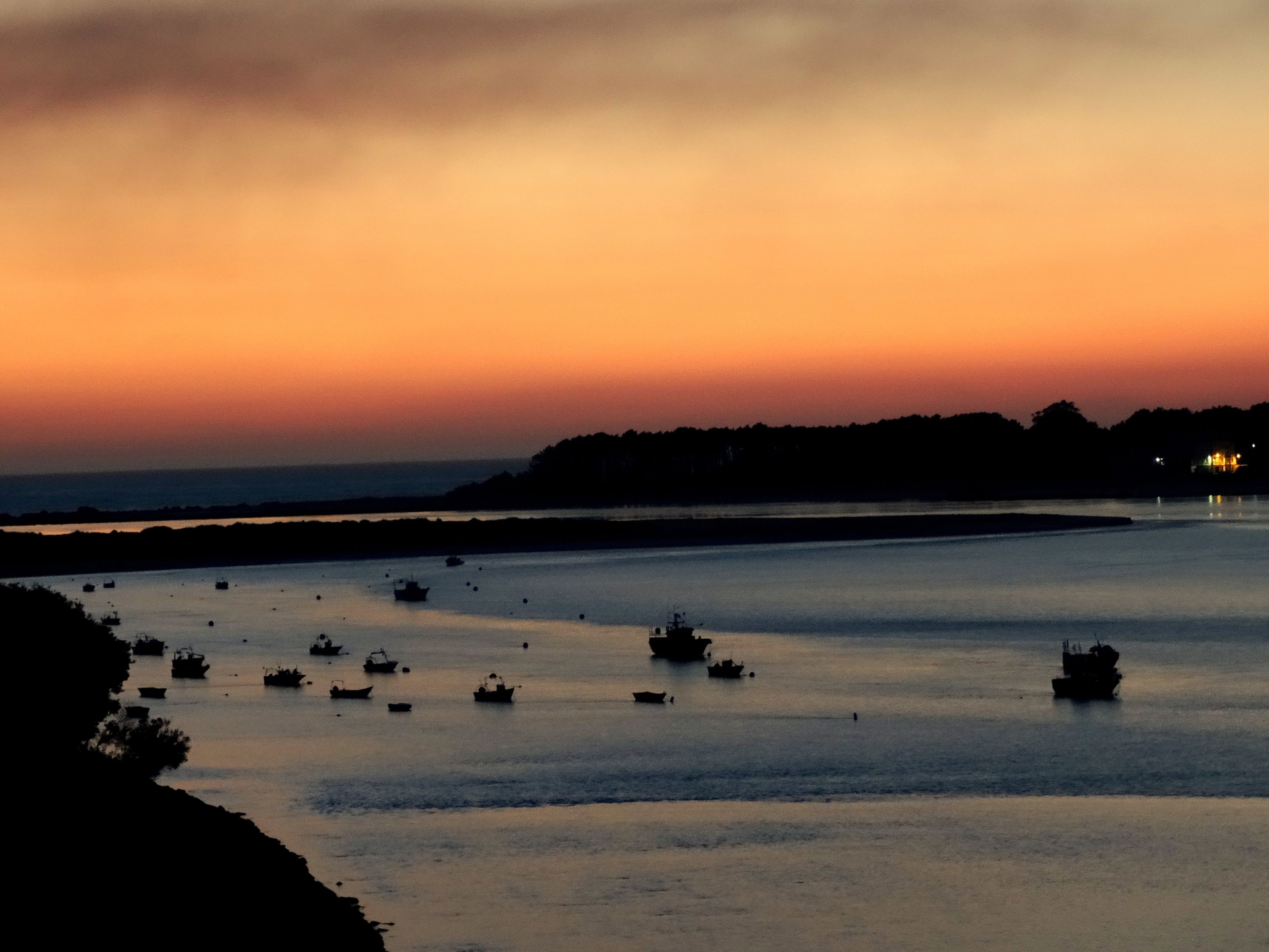 A coastal scene with boats on calm waters during sunset.