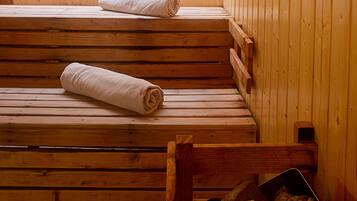 Sala de sauna com bancos de madeira e uma pilha de pedras.
