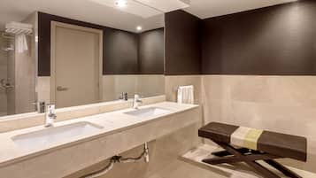 Un baño moderno con dos lavabos, un espejo grande y un banco.