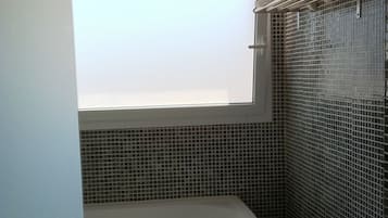 Une salle de bain avec une baignoire, une fenêtre et des murs carrelés.