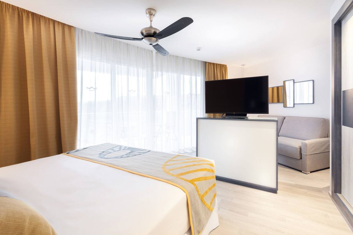 Ein Hotelzimmer mit Bett, Schreibtisch, Fernseher und einer Sitzecke.