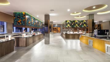 En moderne hotellobby med en lang receptionsdisk, en kaffebar og et stort mural på væggen.