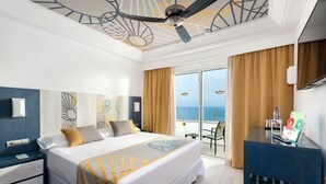 Une chambre d’hôtel avec un lit, un bureau, une chaise et une vue sur l’océan.