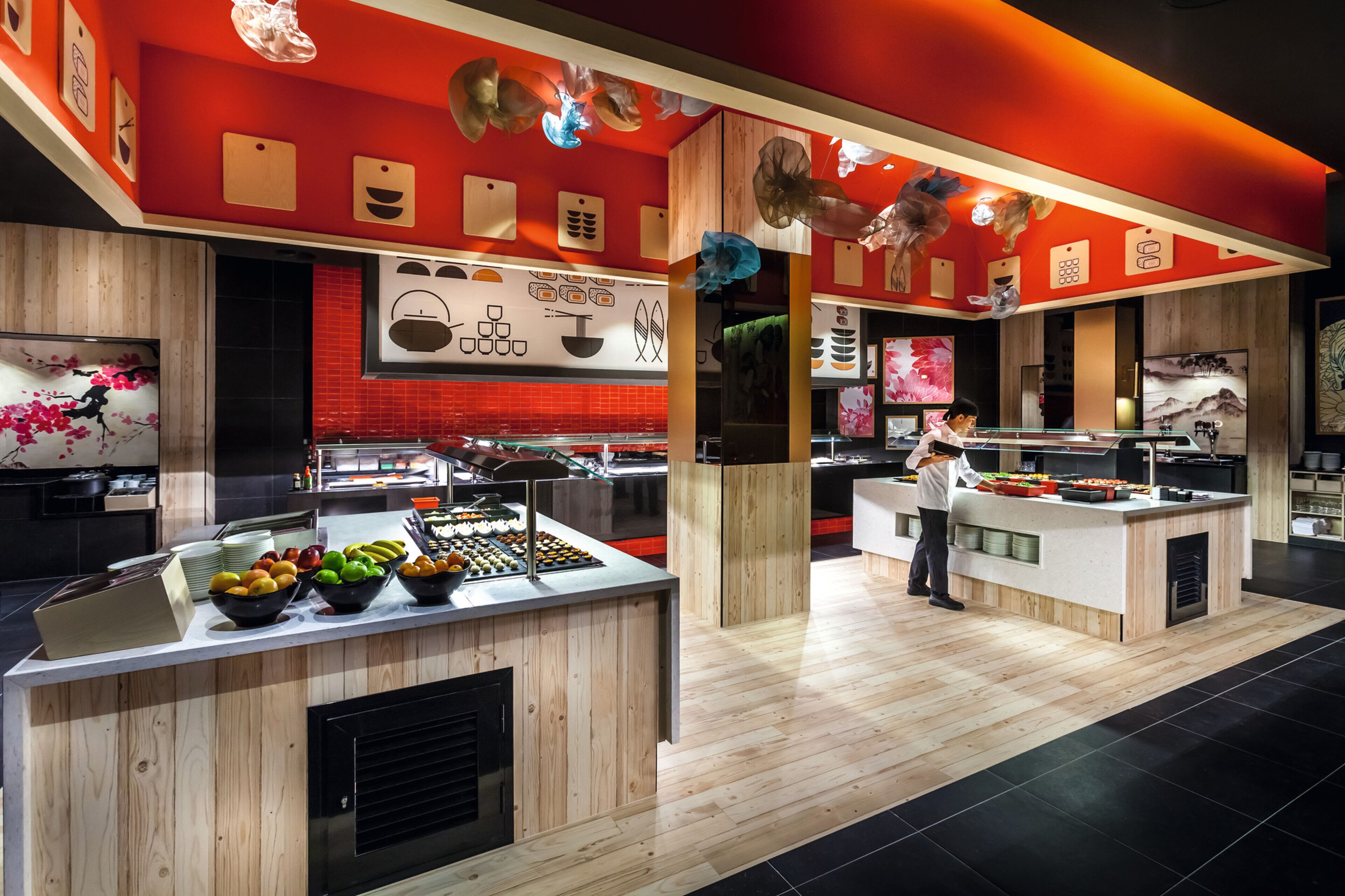 Une cuisine moderne avec des plans de travail en bois, un présentoir à fruits et des œuvres d’art décoratives au mur.