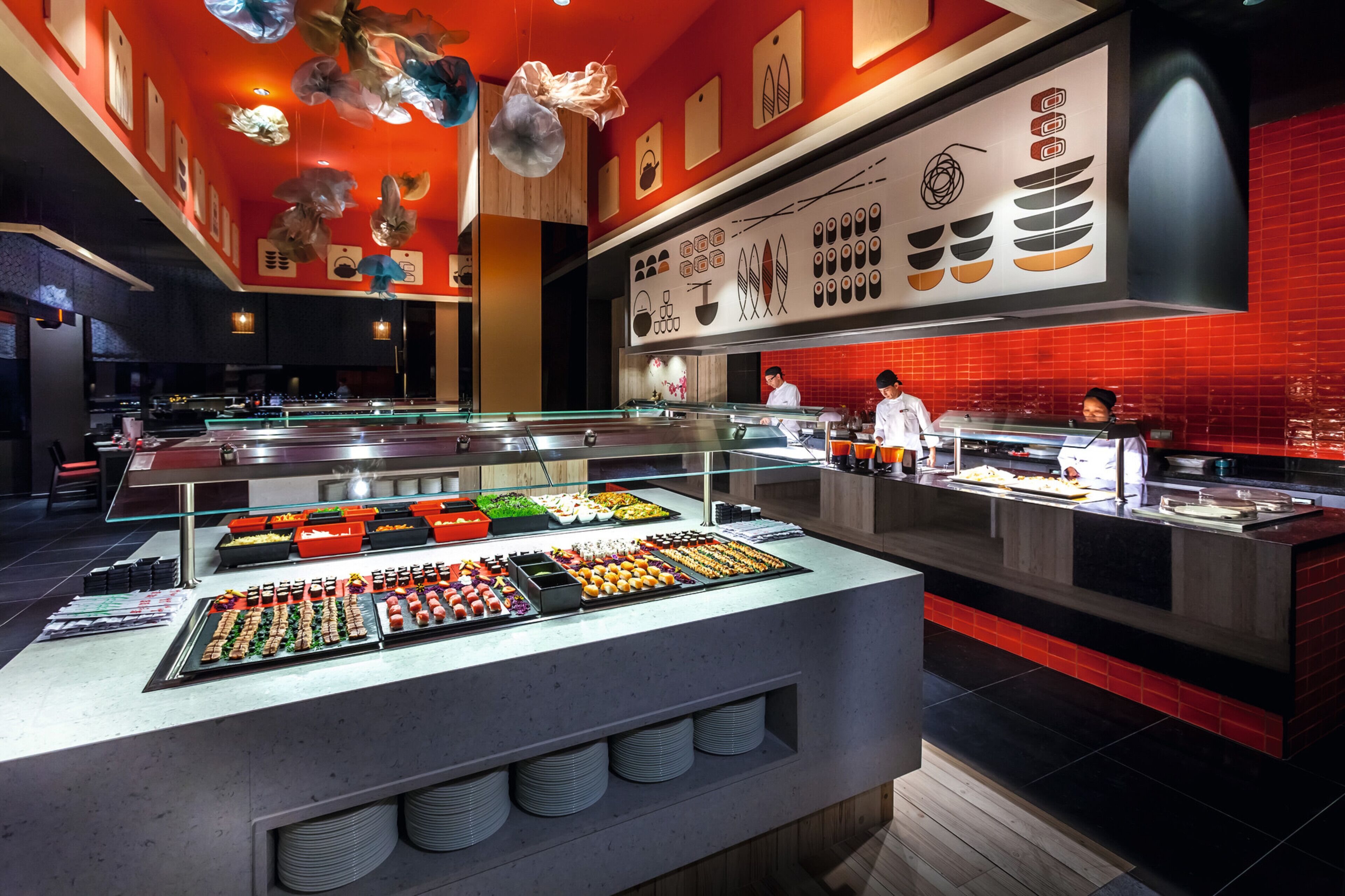 Un área de buffet con diversas opciones de comida y un mostrador donde el personal prepara alimentos.