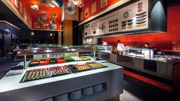 Un área de buffet con diversas opciones de comida y un mostrador donde el personal prepara alimentos.