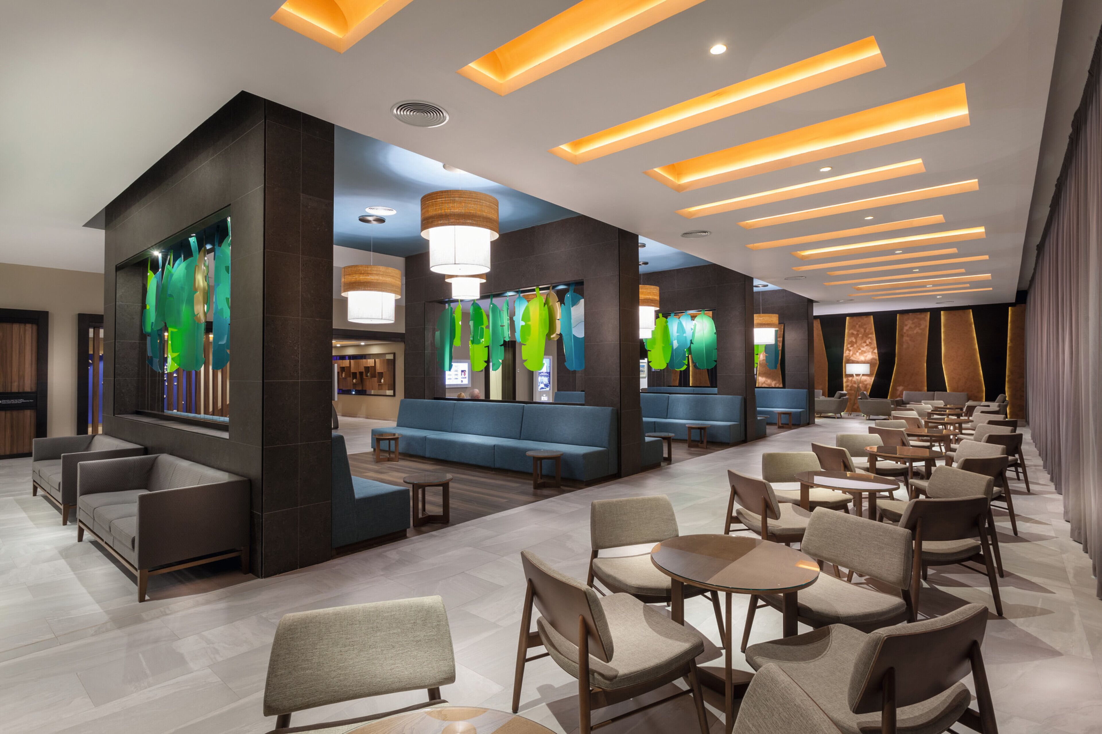 A modern hotel lobby with seating areas, tables, and a reception desk.