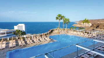 Relax by the oceanfront pool surrounded by palm trees and lounge chairs.