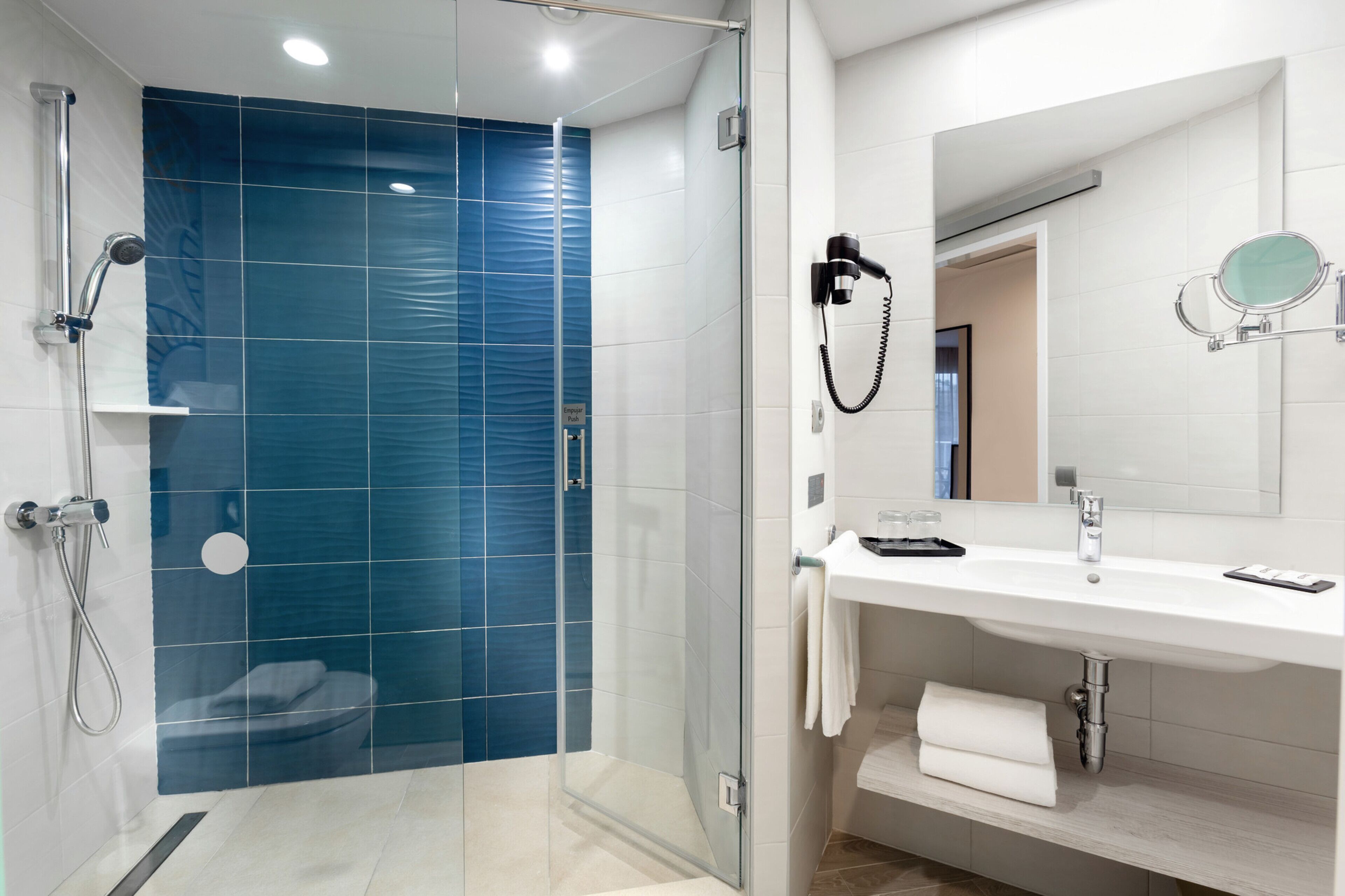 A modern bathroom with a glass-enclosed shower, a white sink, and a mirror.