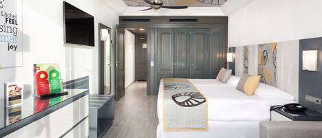 A modern hotel room with a bed, a desk, a chair, and a ceiling fan.