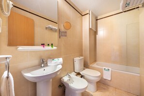 A bathroom with a sink, bidet, toilet, and bathtub. - Apartamentos Lido (Ibiza Town)