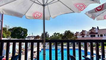 A pool area with umbrellas, lounge chairs, and a view of the pool.