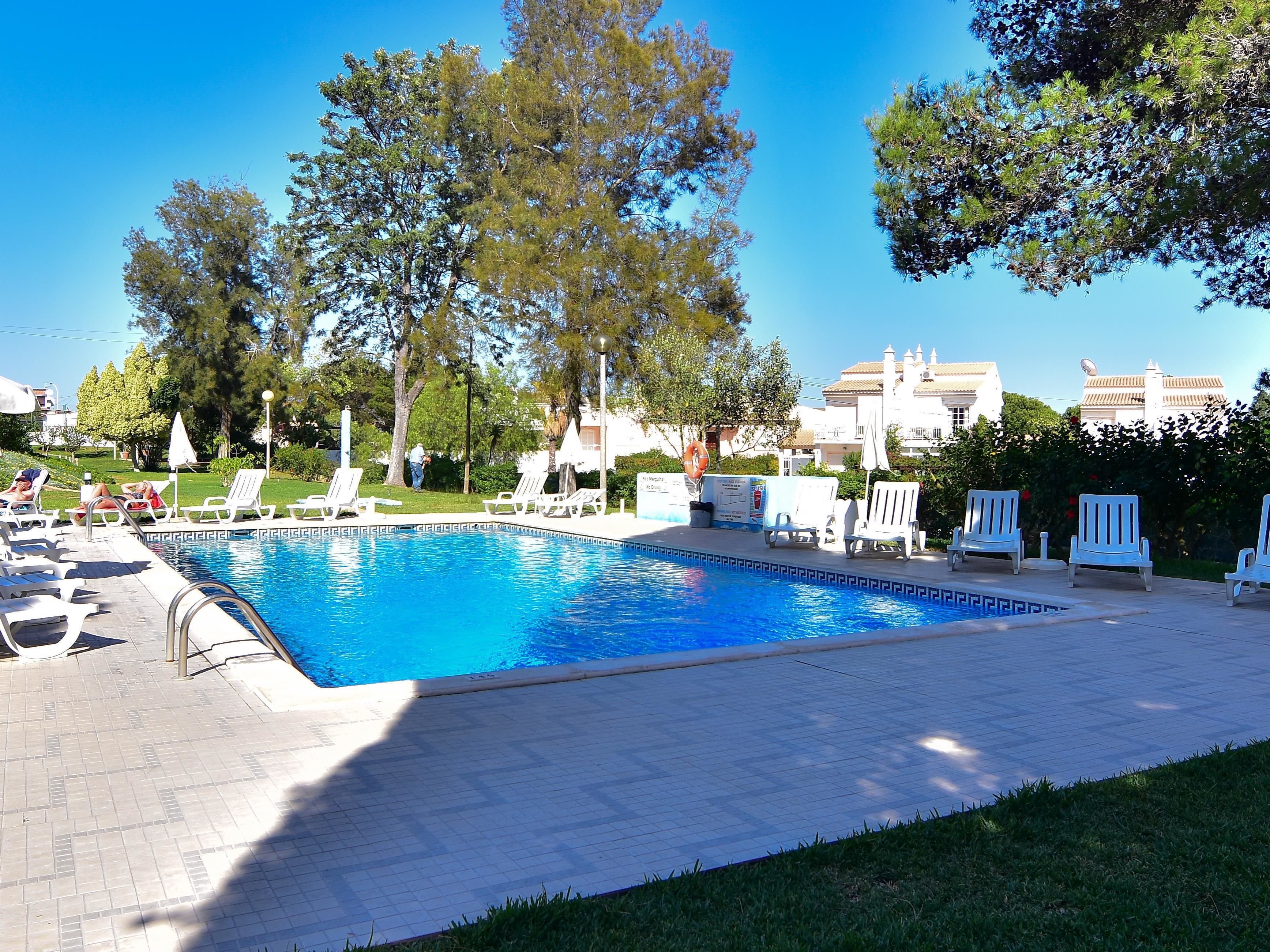 Une piscine avec des chaises longues et une terrasse carrelée.