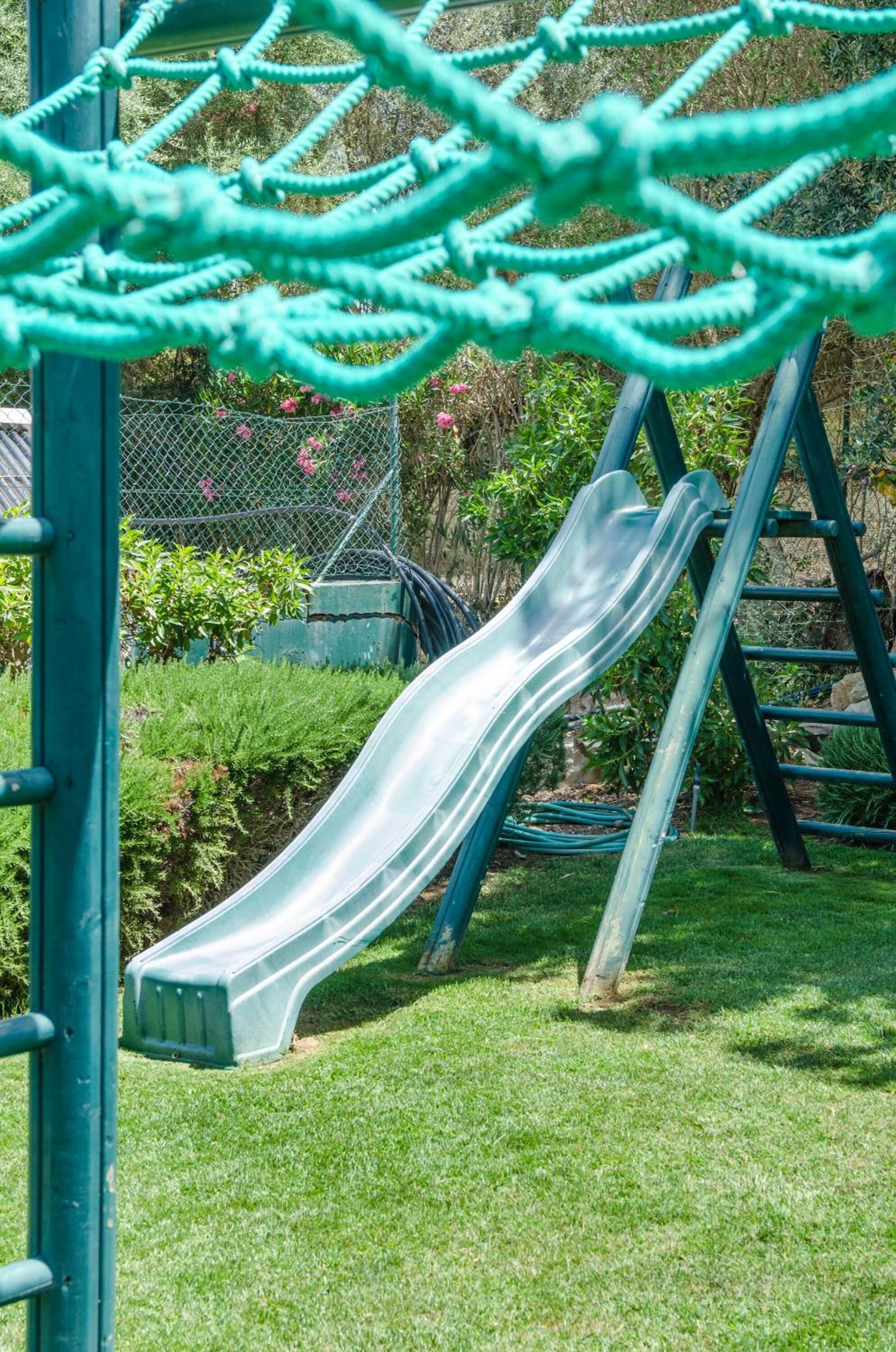 A playground with a slide, net, and a ladder.