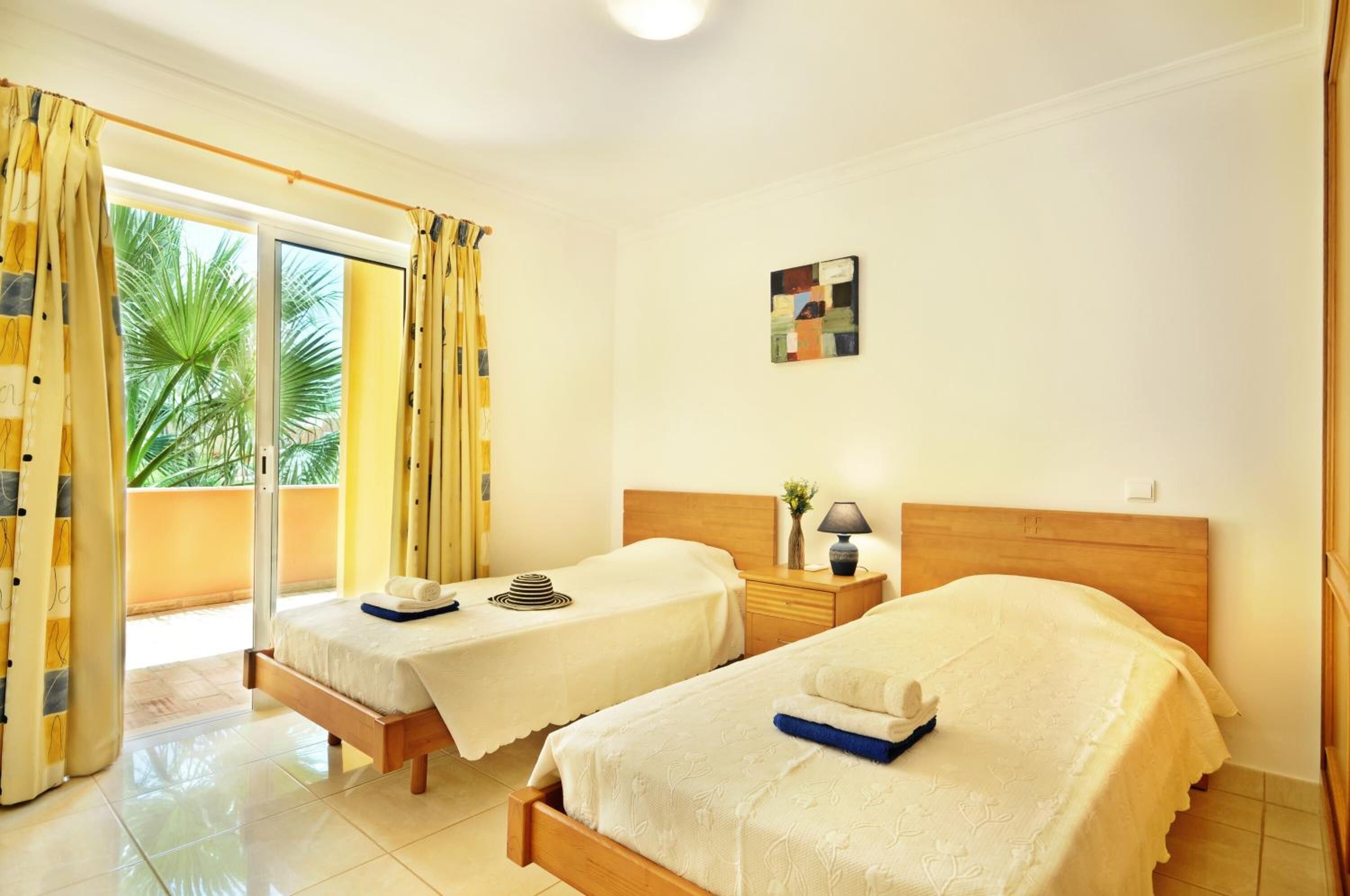 Une chambre d’hôtel avec deux lits, une petite table, une lampe et un tableau au mur.