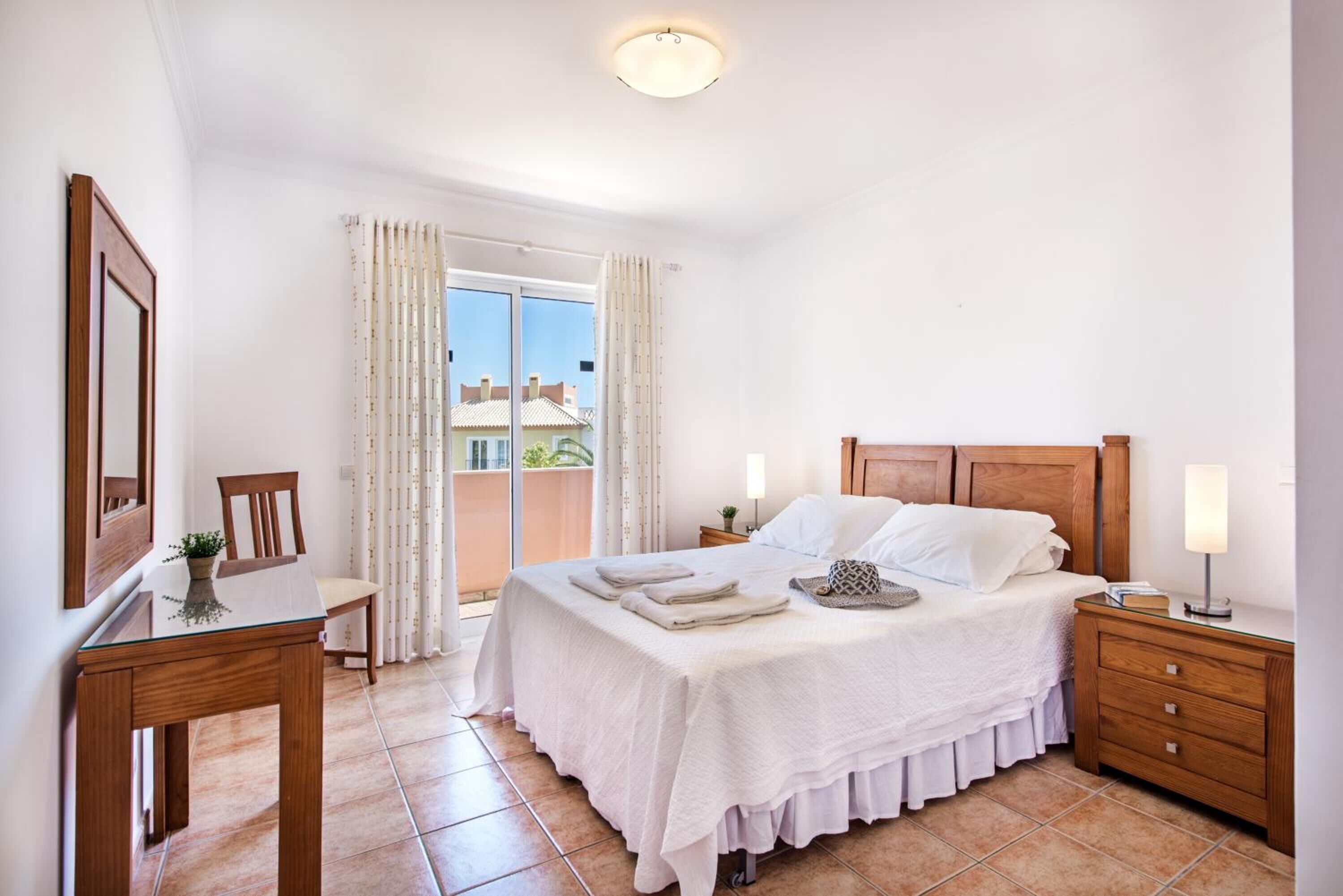 Un dormitorio con cama, mesitas de noche, escritorio y silla.