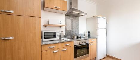 A modern kitchen with wooden cabinets, a built-in microwave, a stove, and a refrigerator.